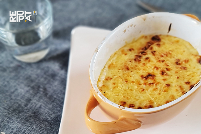 Plat à gratin individuel contenant une endive au jambon gratinée au gruyère