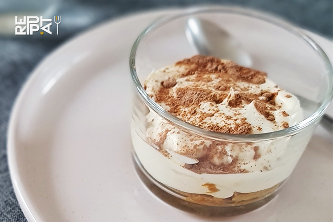 Dessert tiramisu en verrine posé sur une assiette blanche